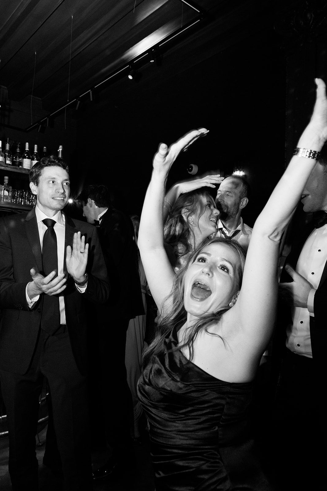 Black and white photos show people dancing and celebrating at a lively party with arms raised in joyful expressions.