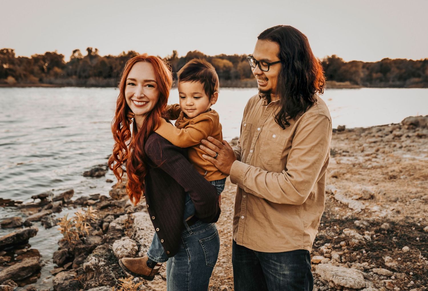 Sara and her husband holding their little boy during a golden-hour fall session.