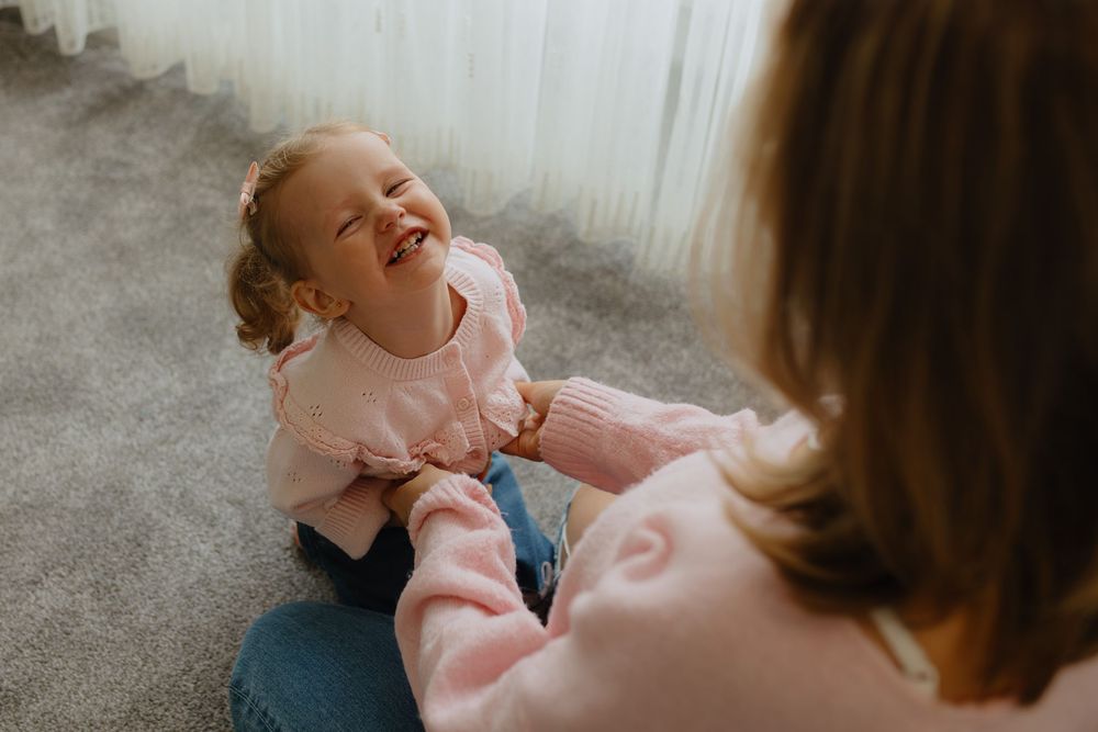 A joyful moment captured between parent and child playing on a gray carpet.