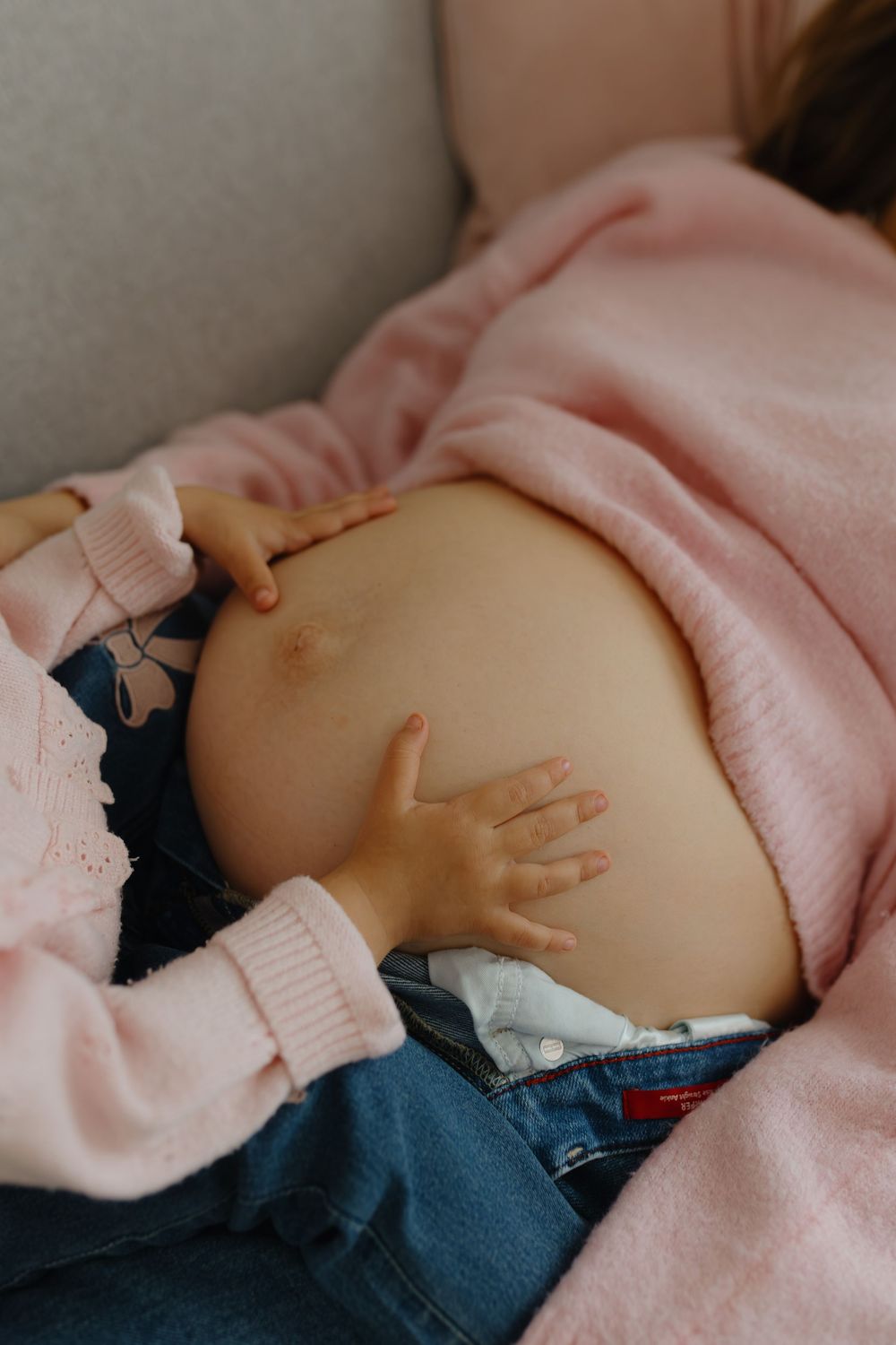 Close-up series of a pregnant belly in a pink sweater showing gentle hand placements and maternal connection.