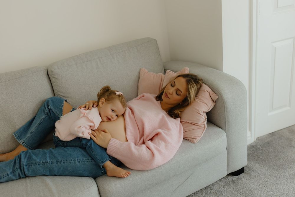 Person in pink sweater resting on white couch in living room.