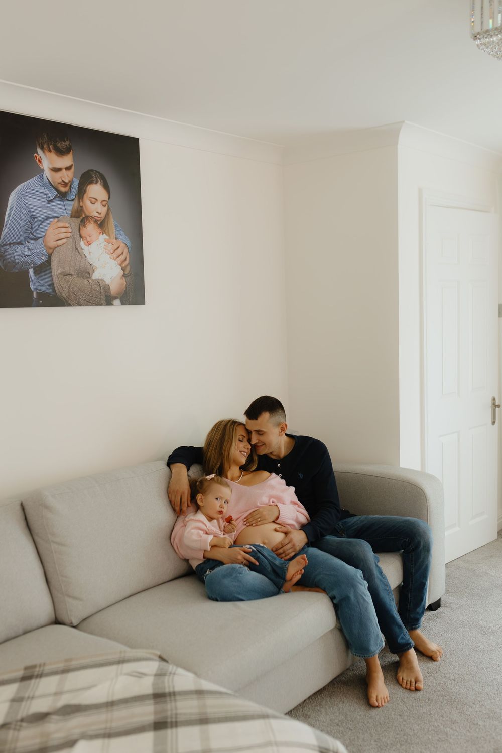 A couple shares intimate moments on a white couch in a minimalist living room setting.