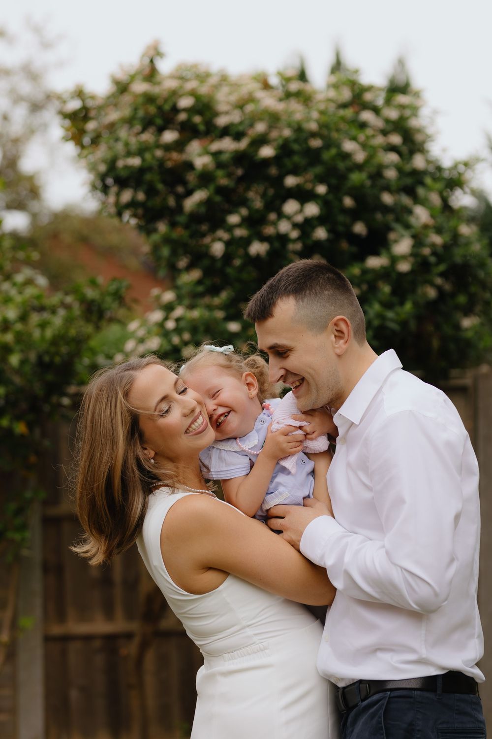 Family shares joyful outdoor moments together in a series of candid shots with their baby in a garden setting.