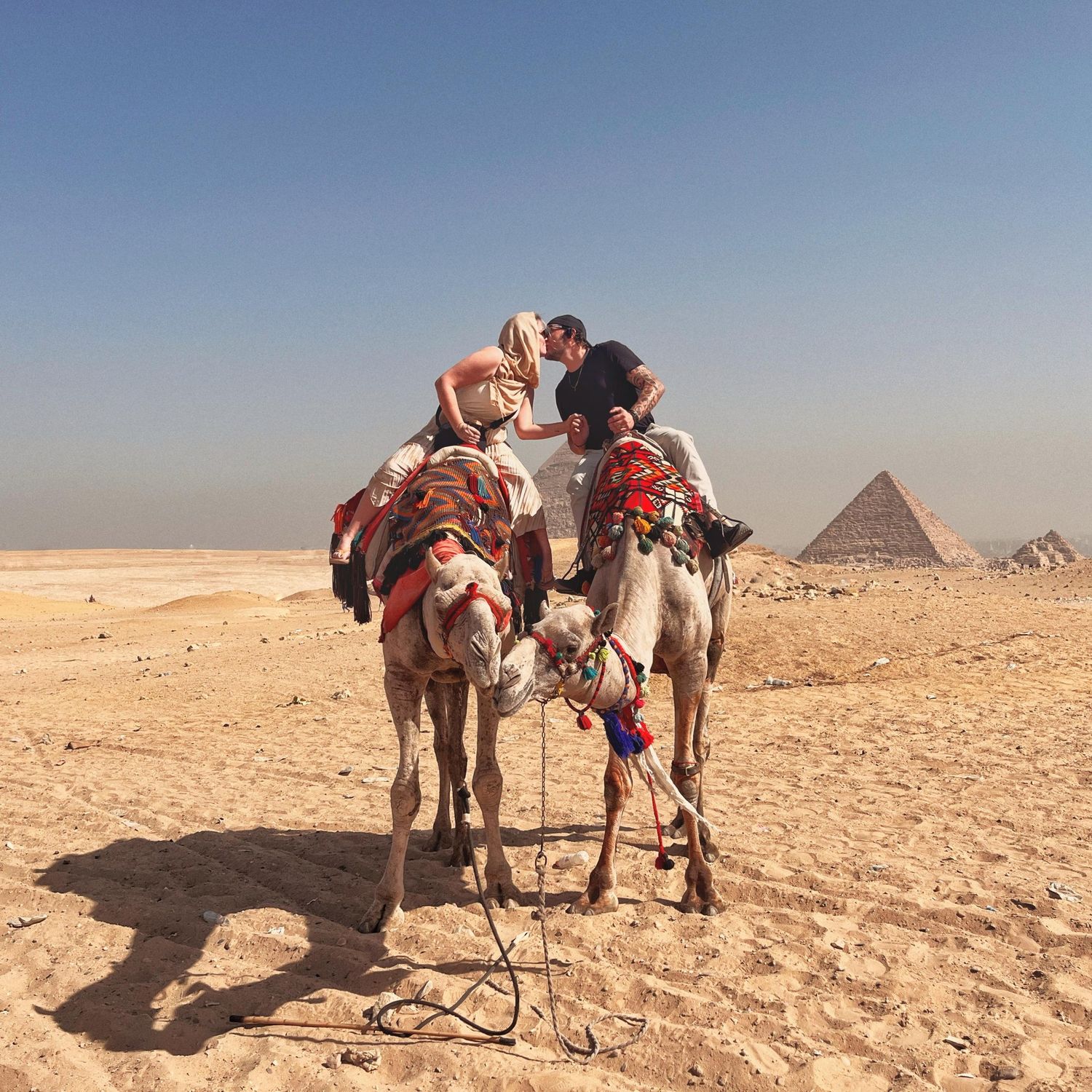 Group of tourists with camels in front of the Egyptian pyramids in the desert.