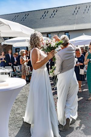 A wedding couple shares a romantic kiss outdoors under a white tent during their celebration.