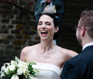 A joyful wedding celebration moment captured against a rustic brick wall backdrop.