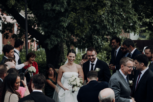 Wedding guests dance together during an outdoor reception celebration in a garden setting.