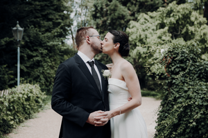 Romantic wedding moment captured in a lush garden setting with greenery in the background.