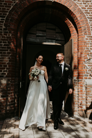 A wedding couple walks through a series of brick archways in a historic building, captured in a sequence of photos.