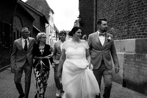 A series of black and white wedding photos showing couples walking along brick walls and alleyways.