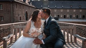 A romantic wedding couple shares intimate moments on a rustic wooden bridge in a scenic outdoor setting.