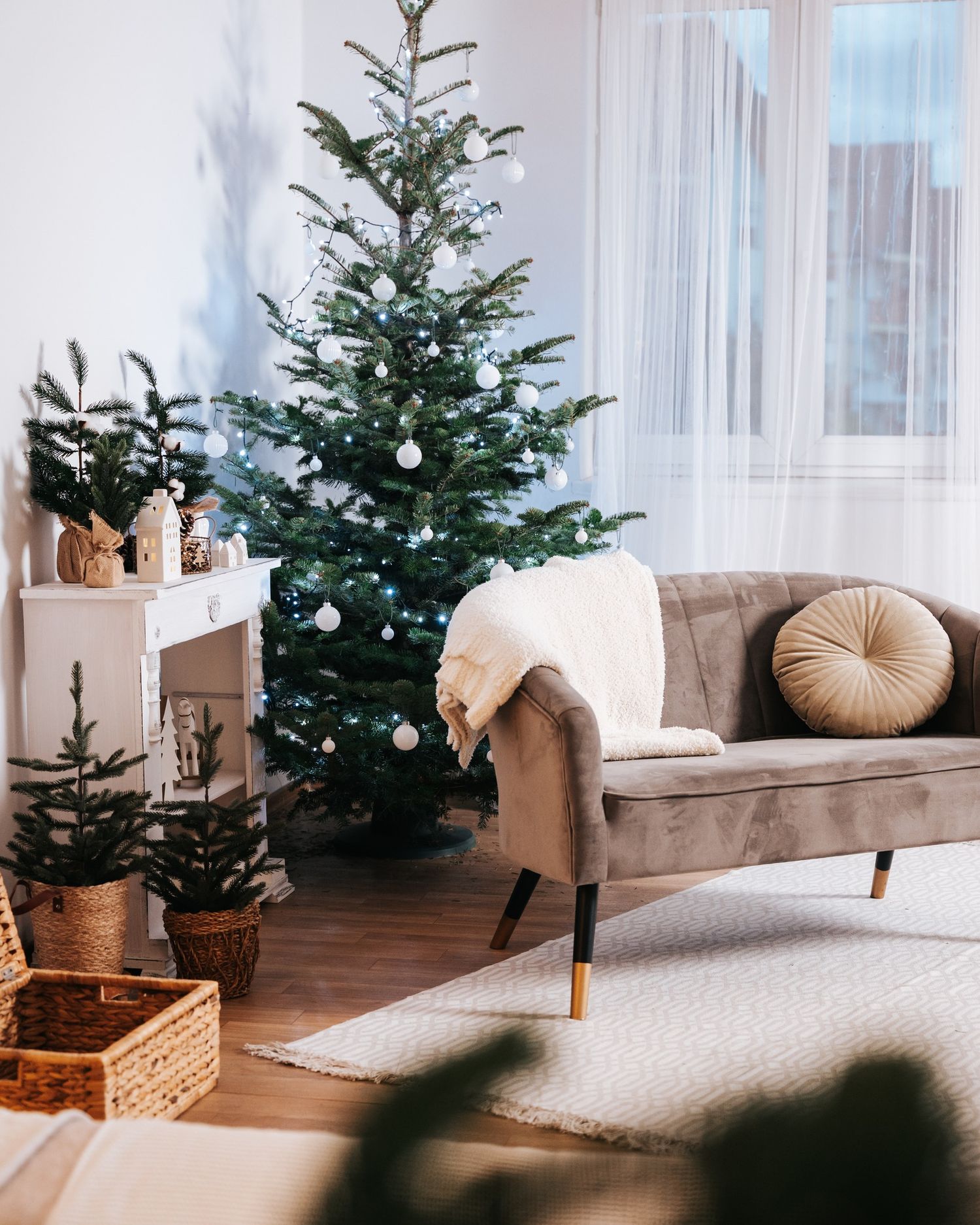 A cozy living room decorated with natural Christmas trees, beige furniture, and soft pillows in a minimalist style.