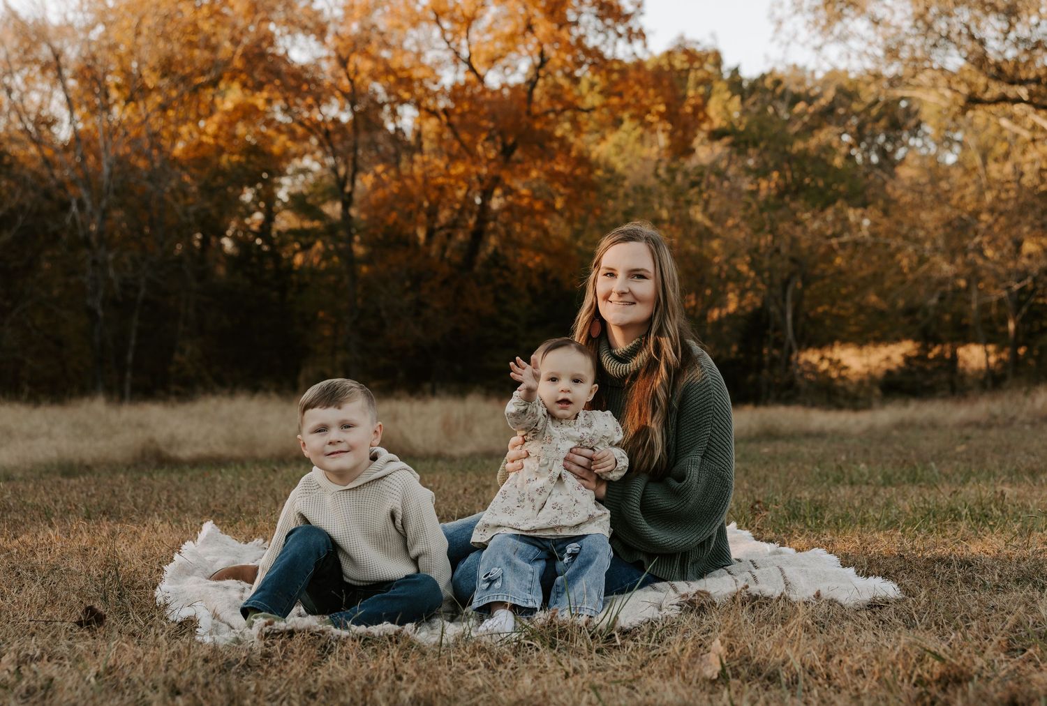 Family lying together on white blanket during autumn outdoor photo session.