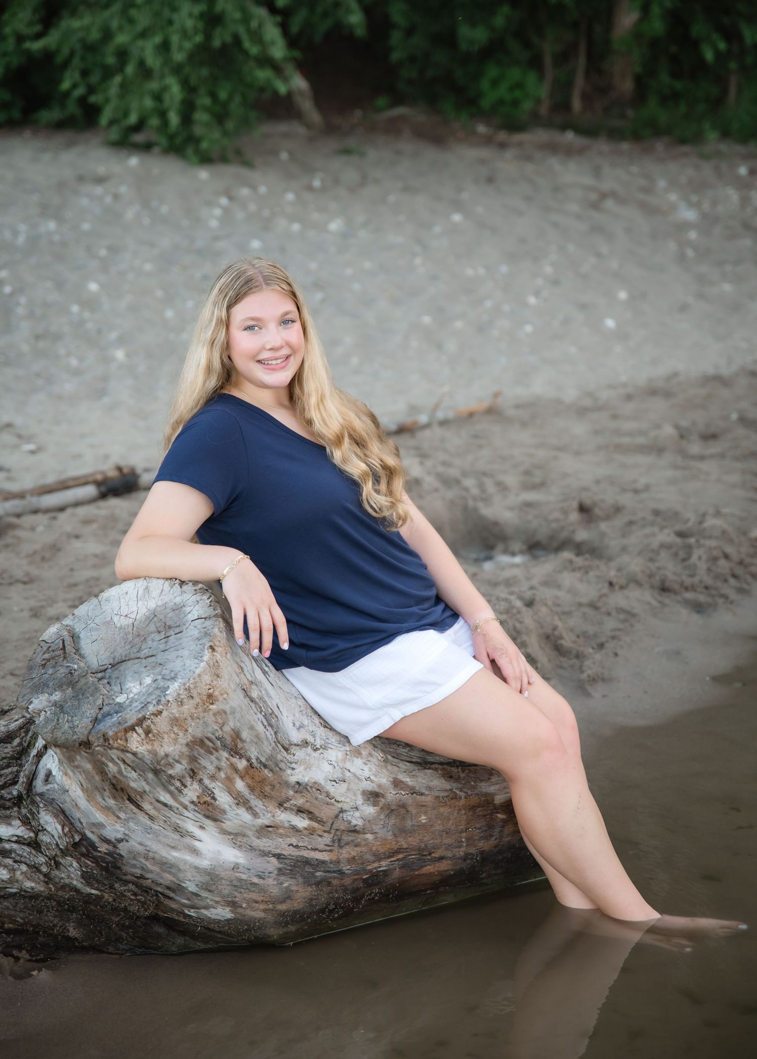 A series of artistic beach portraits showing someone posing on a large driftwood log at the water's edge.