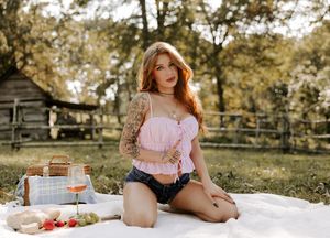 Picturesque picnic scene with pink clothing and vintage accessories in natural setting.