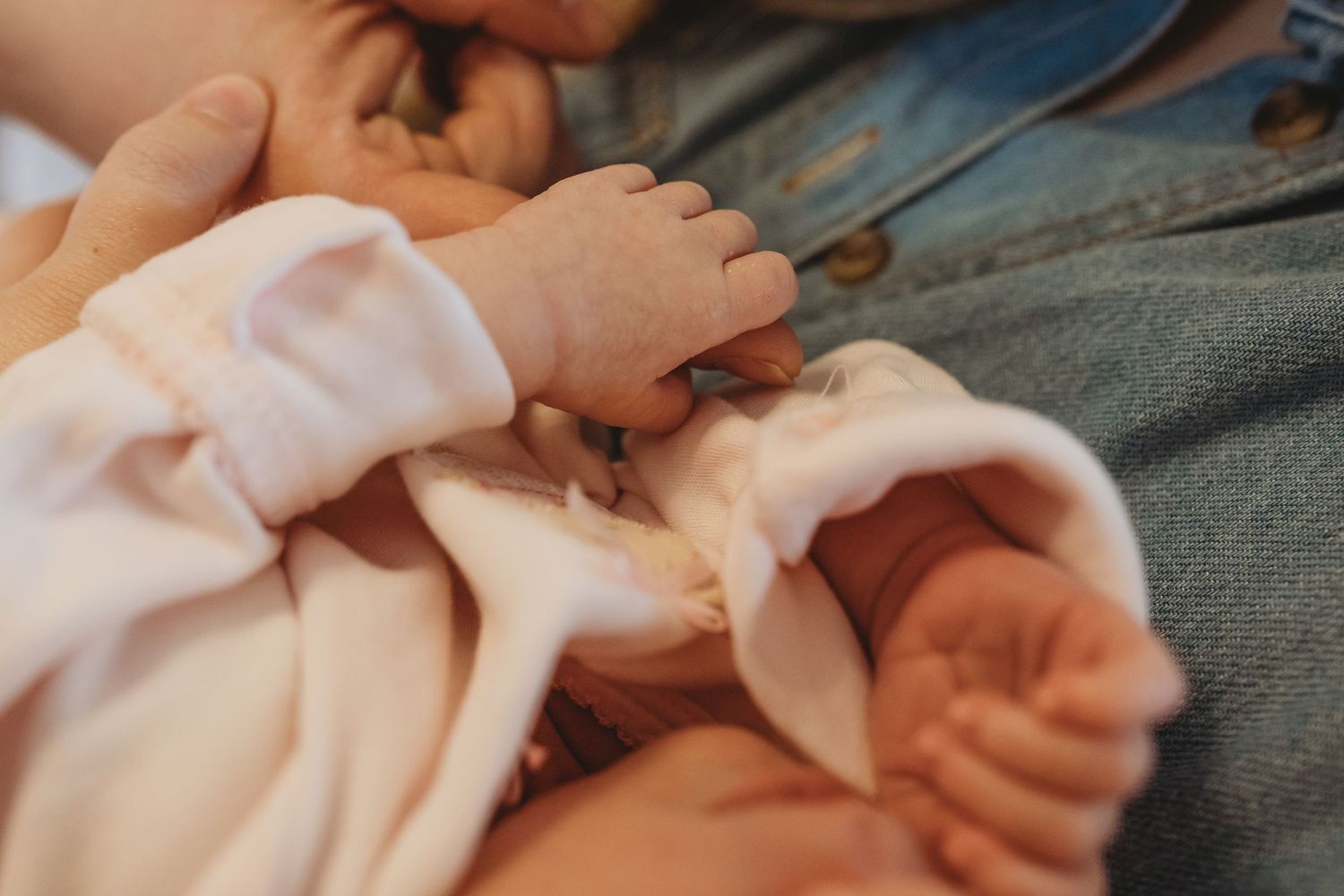 Tender moment captured during newborn photography session with soft pink tones.