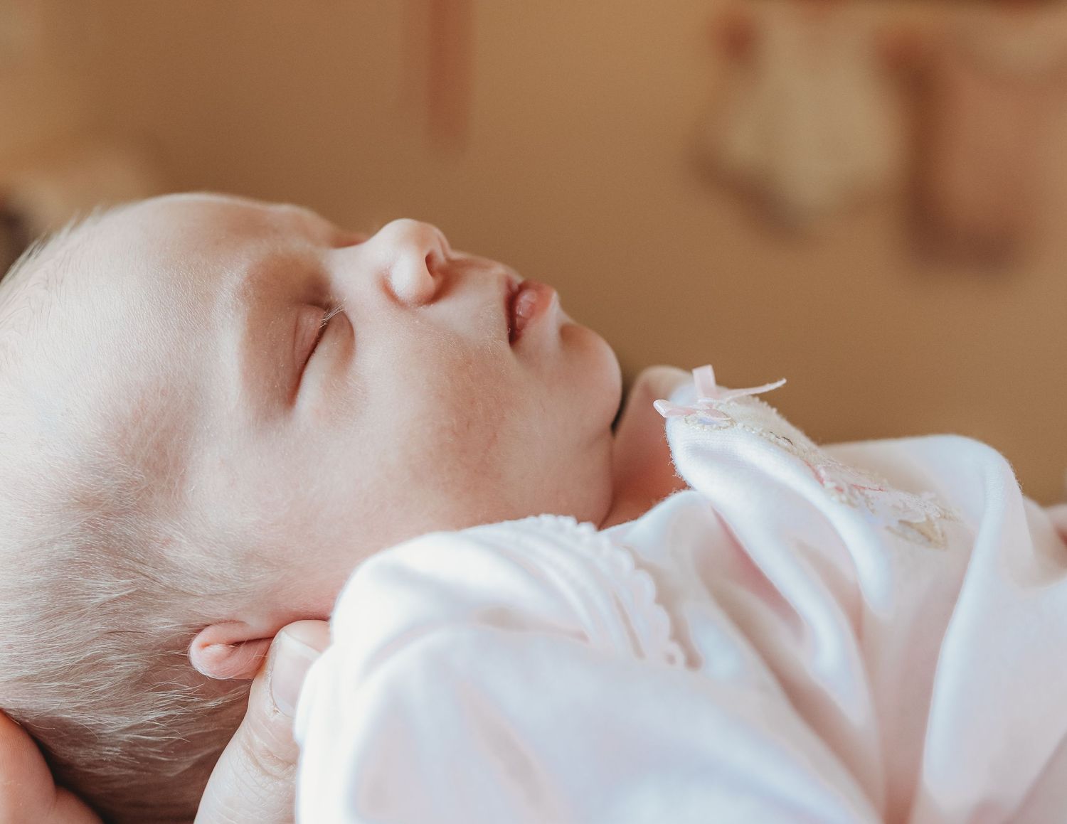 Serene newborn photography with soft natural lighting and white clothing.