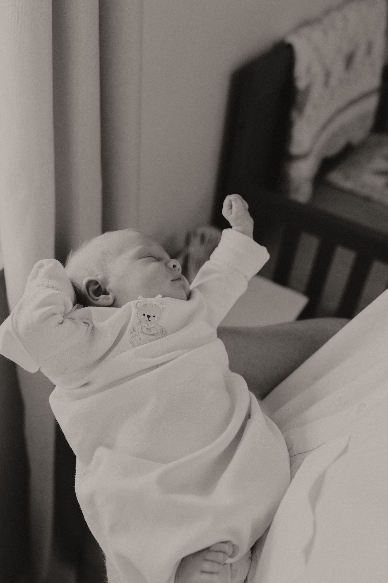 Black and white portrait of sleeping newborn in white swaddle blanket.