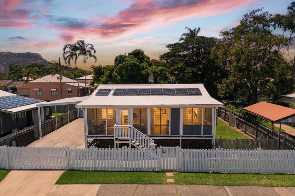 Luxury waterfront homes with modern architecture and glass walls showcase stunning sunset views over calm waters.