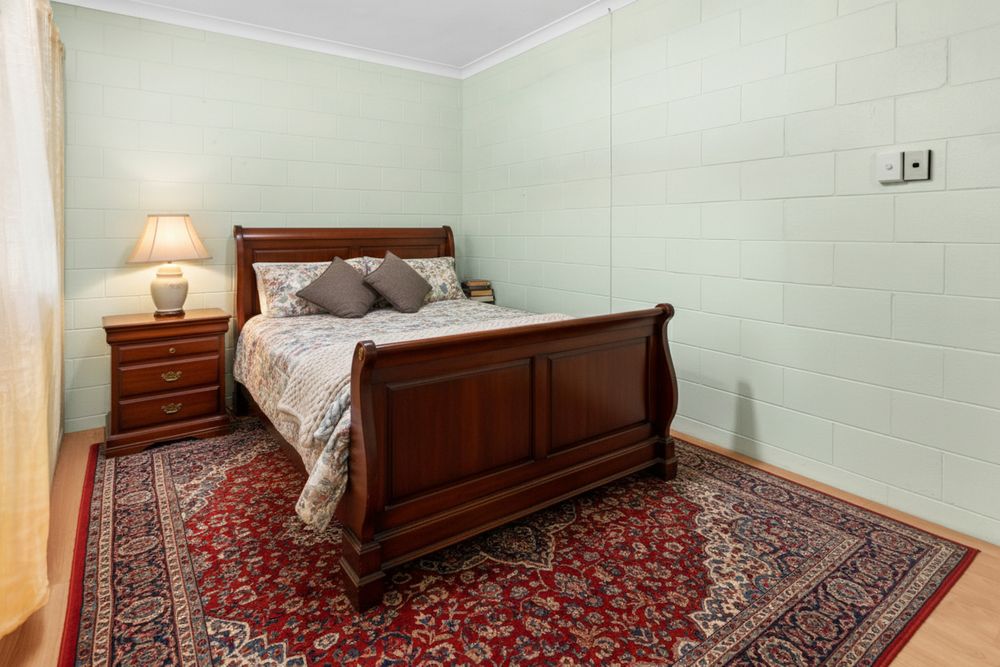Elegant bedroom with sleigh bed, oriental rug, and mint green walls showcasing a classic traditional design style.