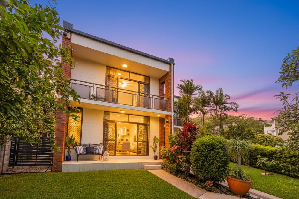 Modern luxury home exterior with landscaped garden and warm lighting at dusk creates an inviting ambiance.
