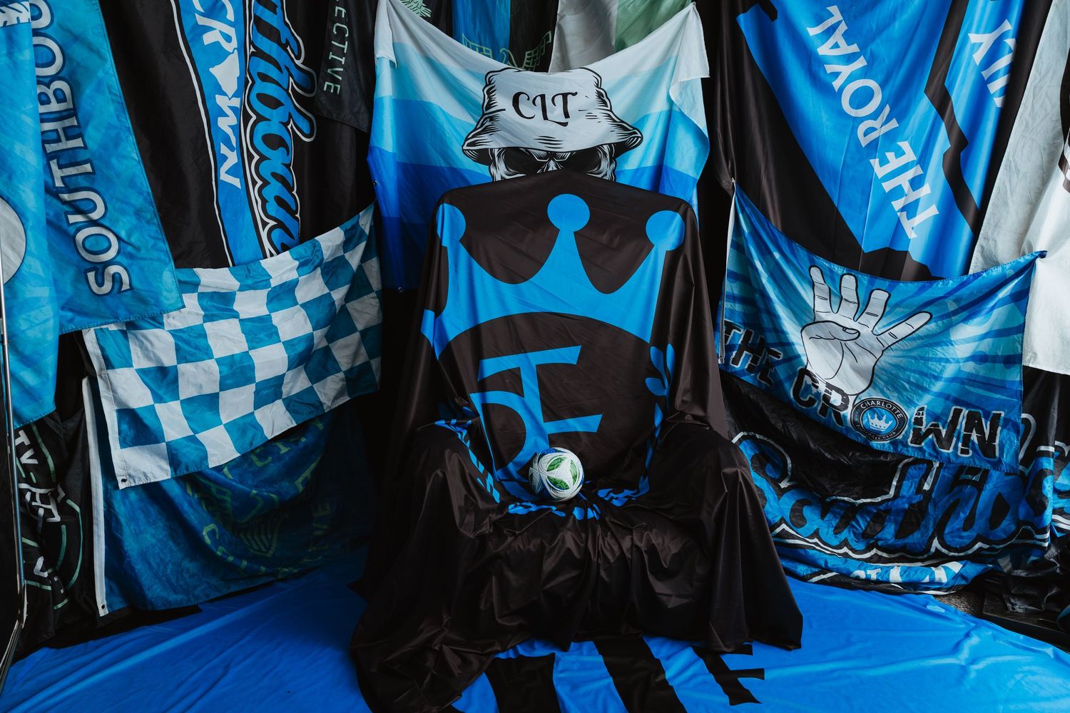 Charlotte FC crown logo jersey displayed among blue and white supporter flags and banners.