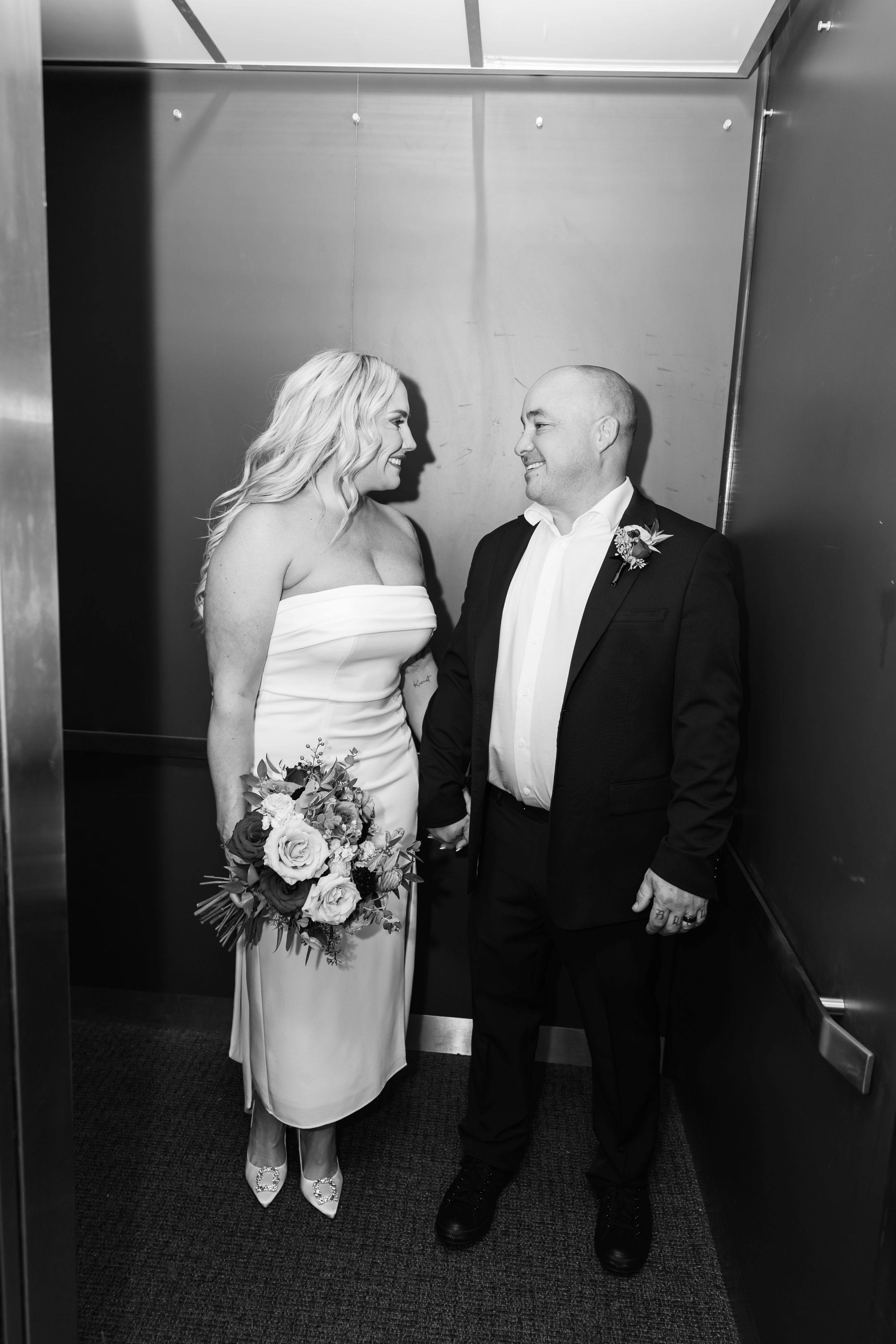 A black and white photo of a couple sharing an intimate moment in an elevator.