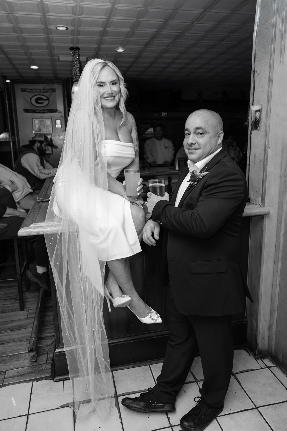 A bride and groom share their first dance together at their wedding reception on a white tiled dance floor.