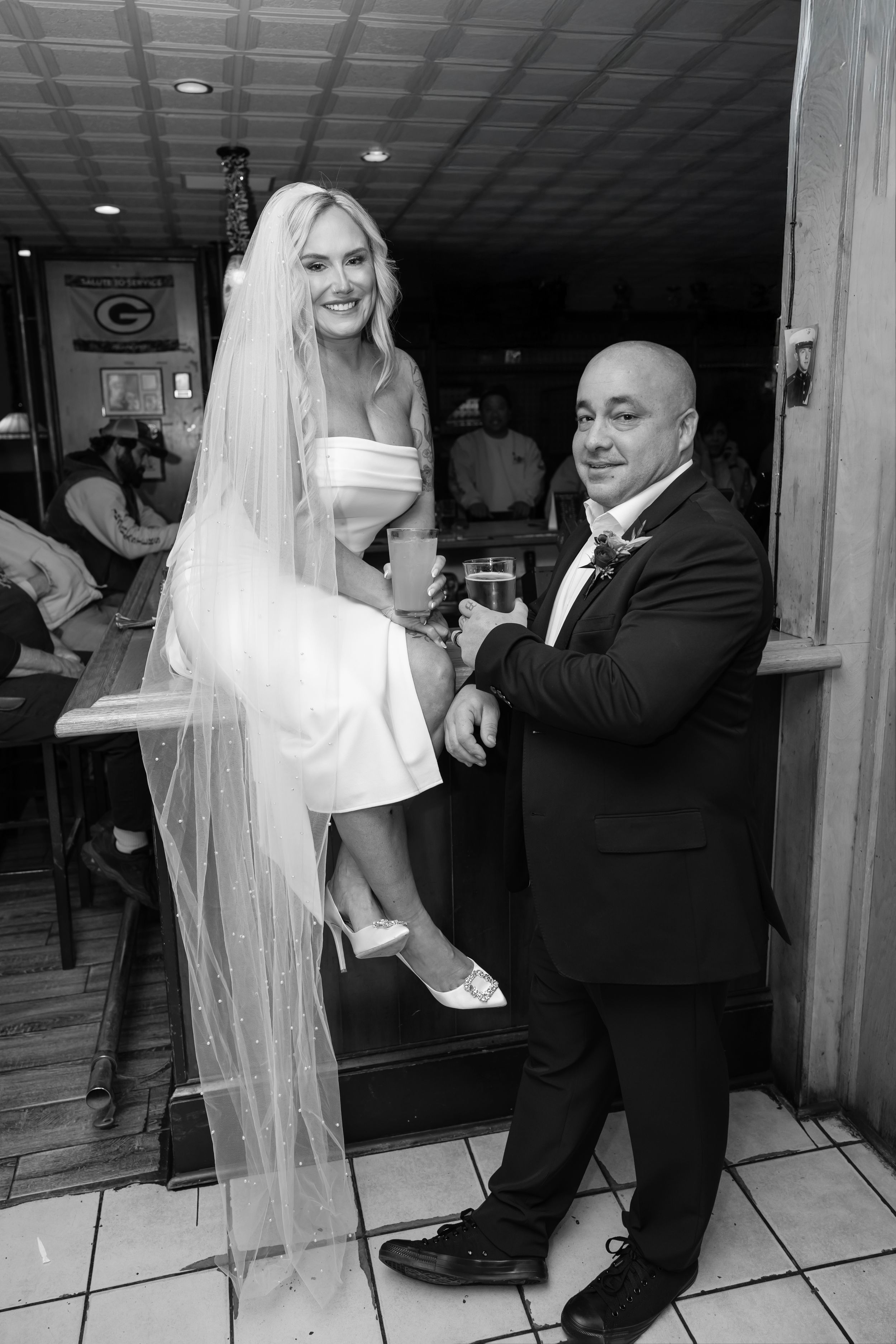 A bride and groom share their first dance together at their wedding reception on a white tiled dance floor.