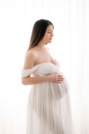Silhouette rétroéclairé d’une future maman en robe de voilages blancs