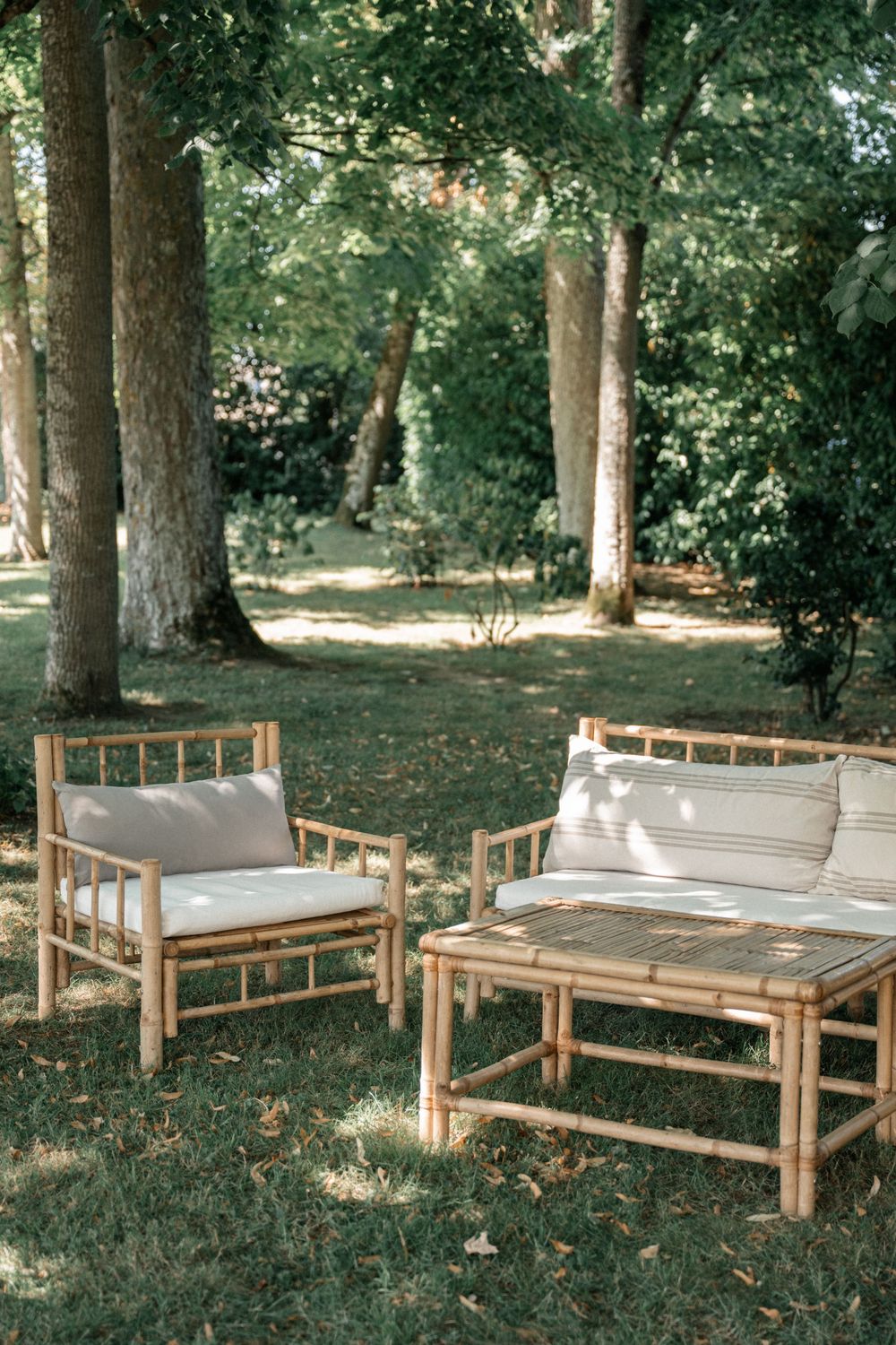 Wooden benches arranged in a shaded outdoor garden setting with trees in the background.