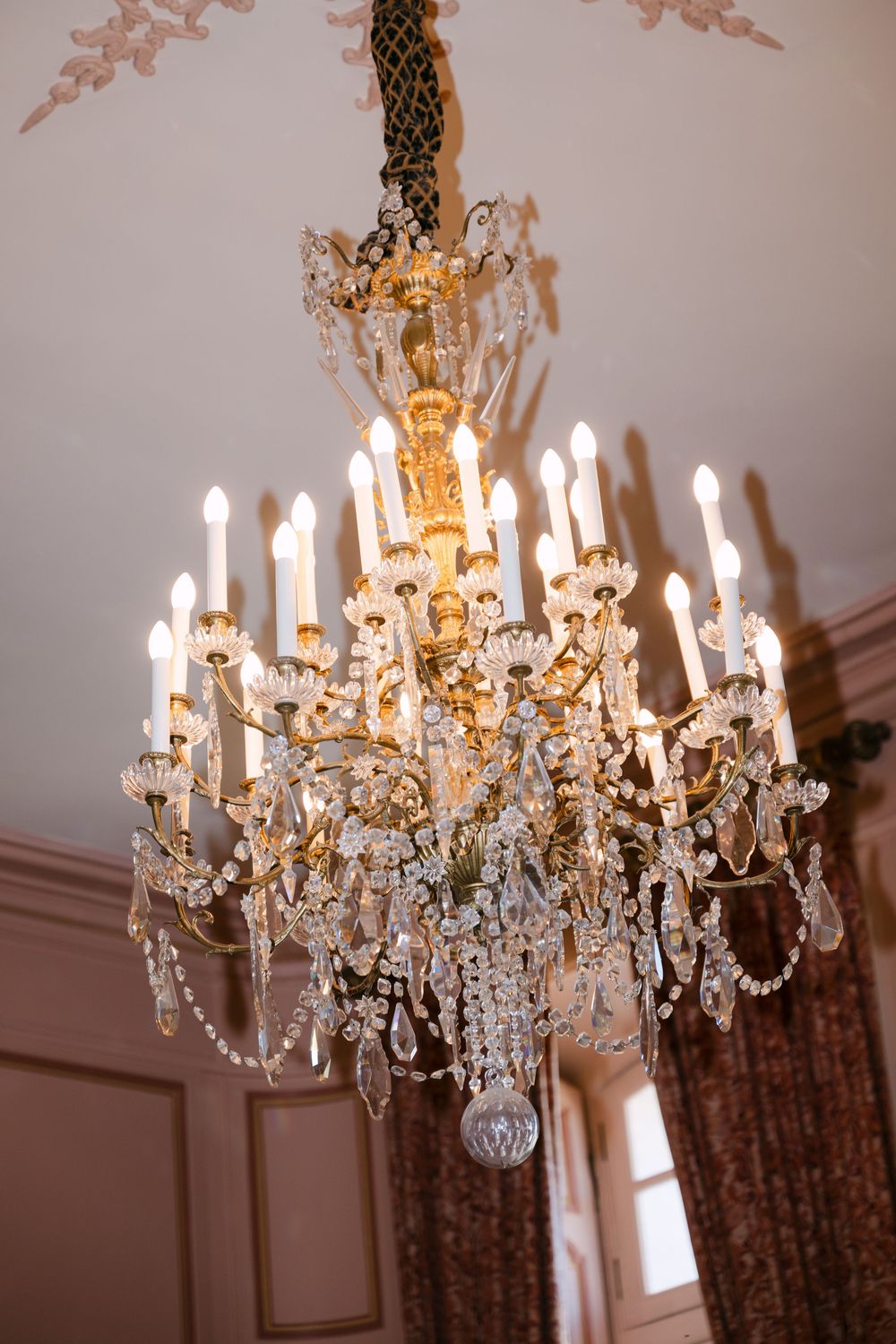 Elegant crystal chandelier with multiple tiers of hanging crystals and lit candles photographed in sequence.
