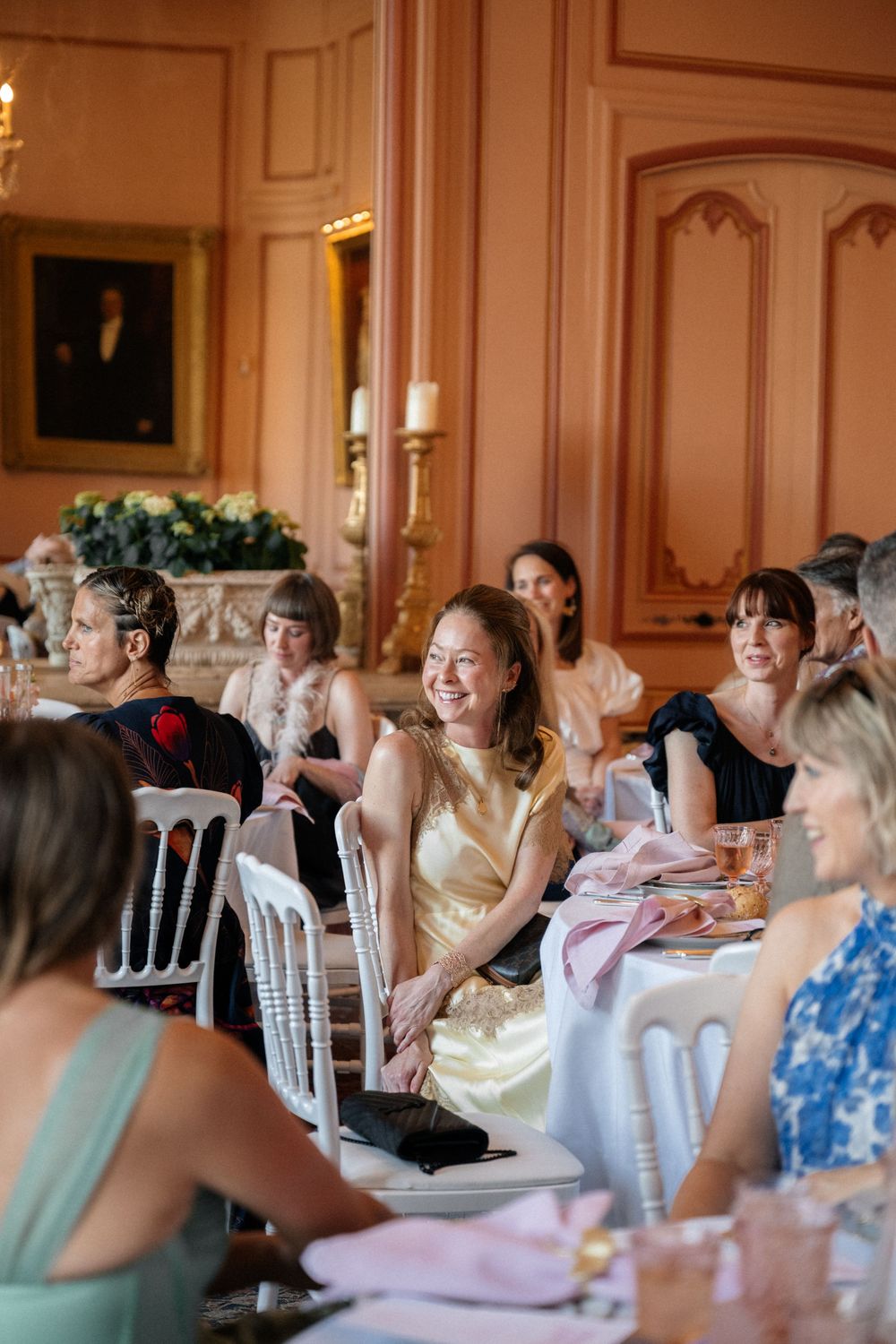 Guests seated at formal dining tables in an elegant ballroom with ornate decor and candlelight.