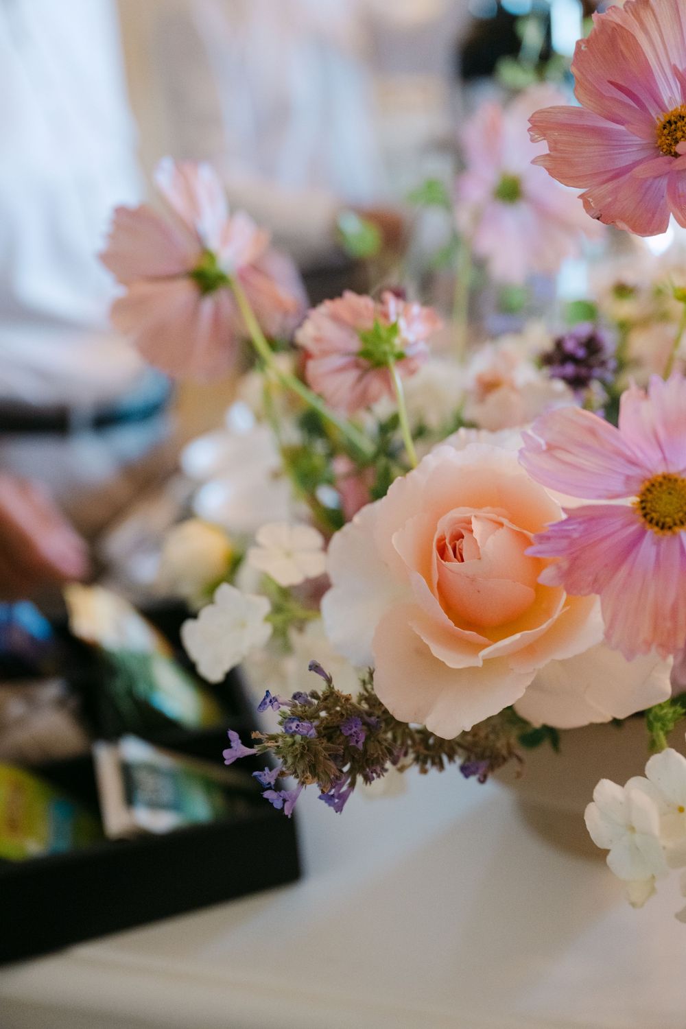 Delicate pink and peach flowers including roses and cosmos arranged in a soft, romantic garden style display.