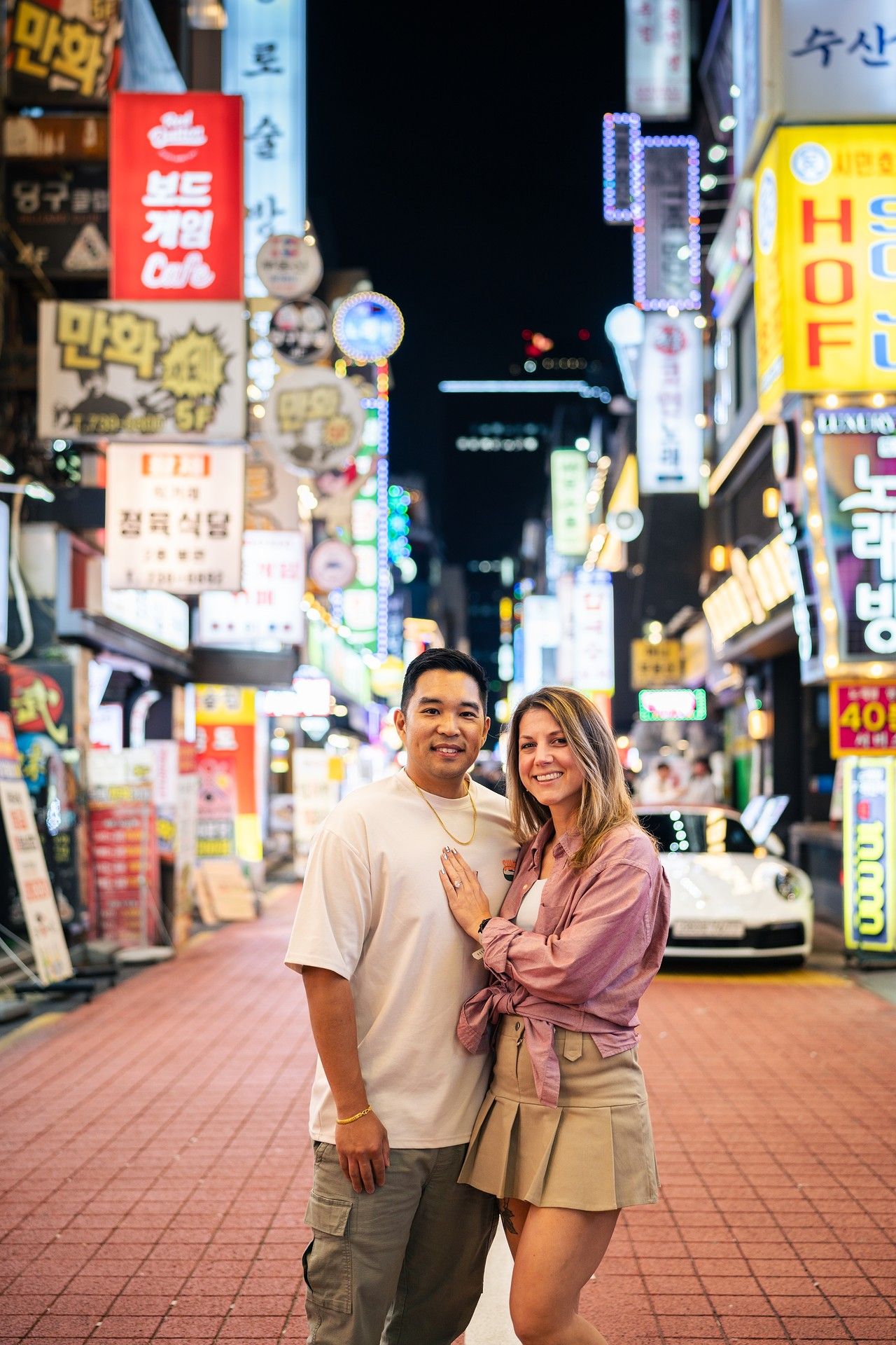 People enjoying a lively evening on a neon-lit street in South Korea with colorful signage and storefronts.