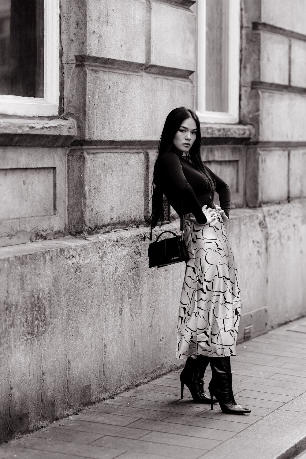 A black and white photo sequence shows a person in a patterned dress sitting and checking their phone against a concrete wall.