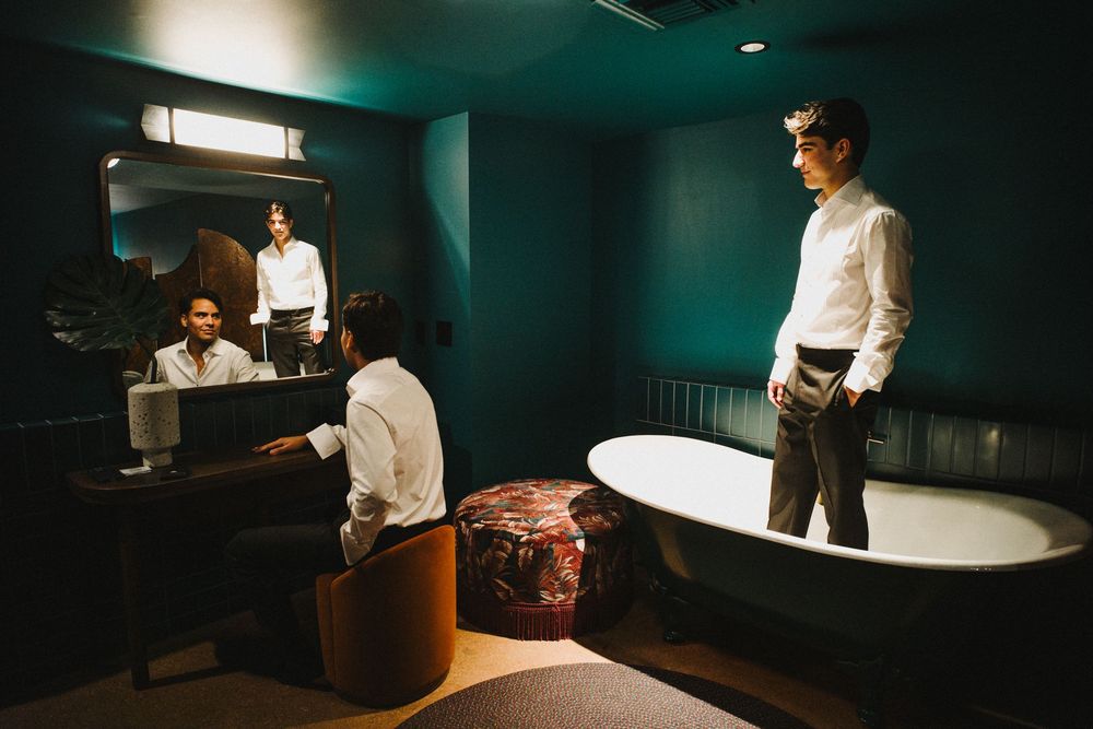 People in white dress shirts gather in a dimly lit room with teal walls and modern decor.
