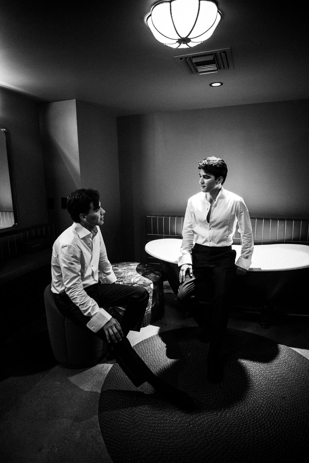 A dramatic black and white photo sequence shows a person in white moving across a dark room with moody lighting.