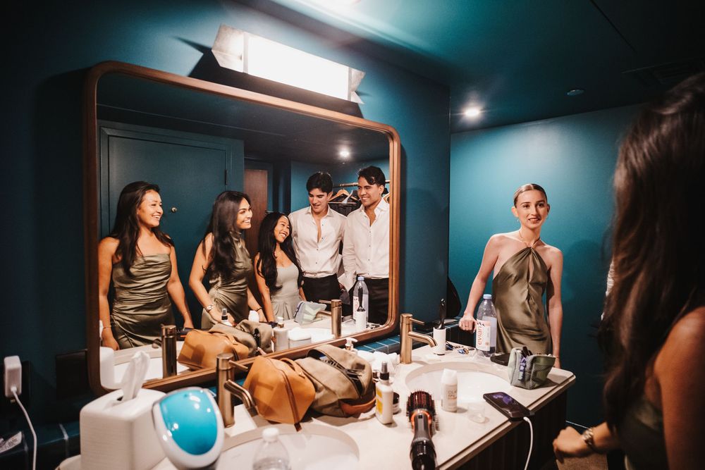 A group gathers in a dimly lit room with teal walls for an intimate social gathering.