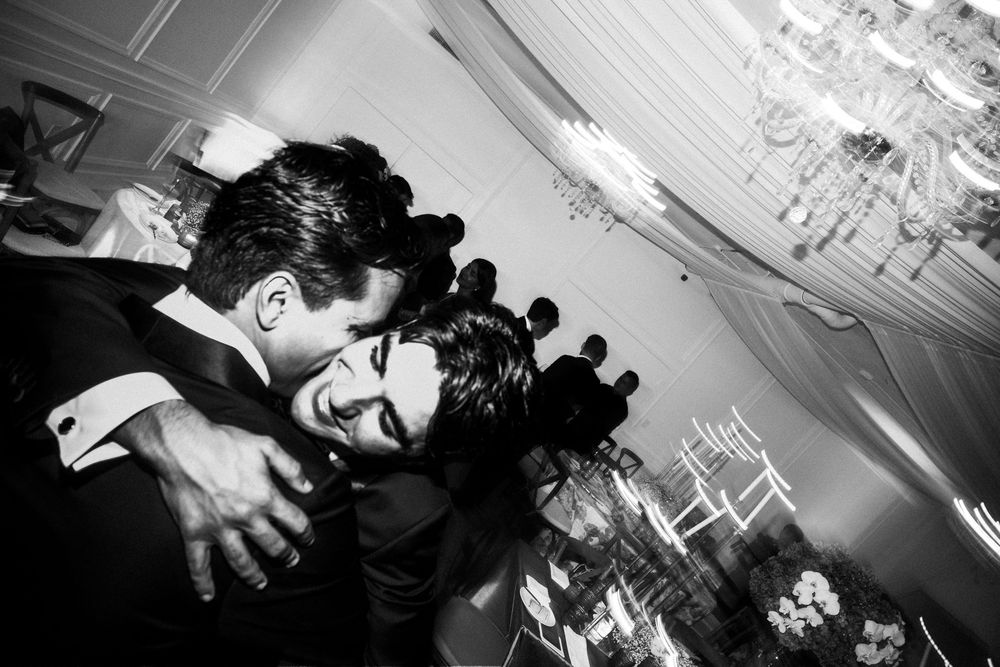 Black and white photograph showing people dancing and celebrating at a lively party reception.