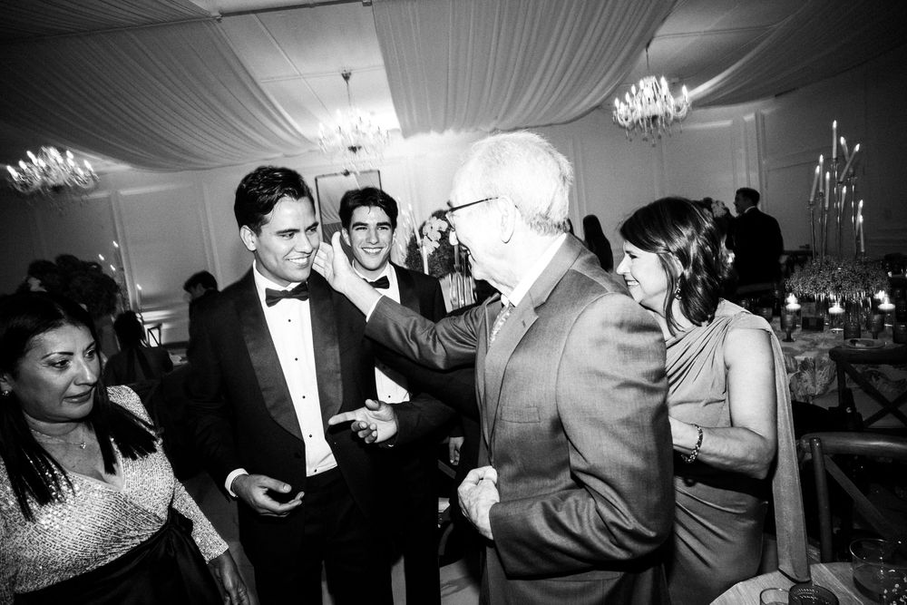 People dancing and celebrating at an elegant wedding reception in a dimly lit tent venue.