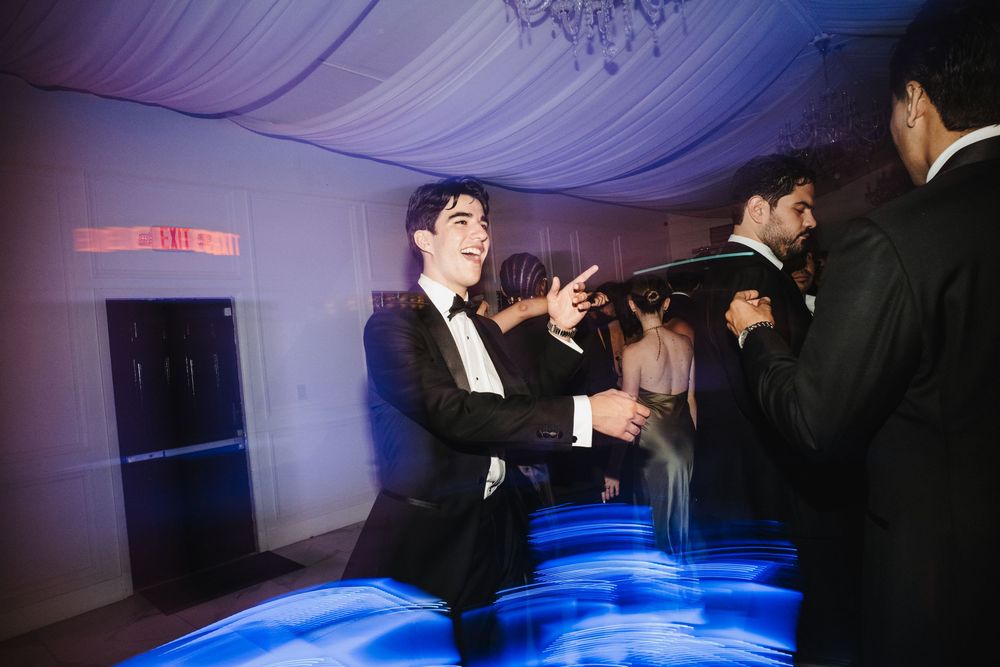 People dancing and celebrating at an elegant event with purple lighting and blue reflections on the dance floor.