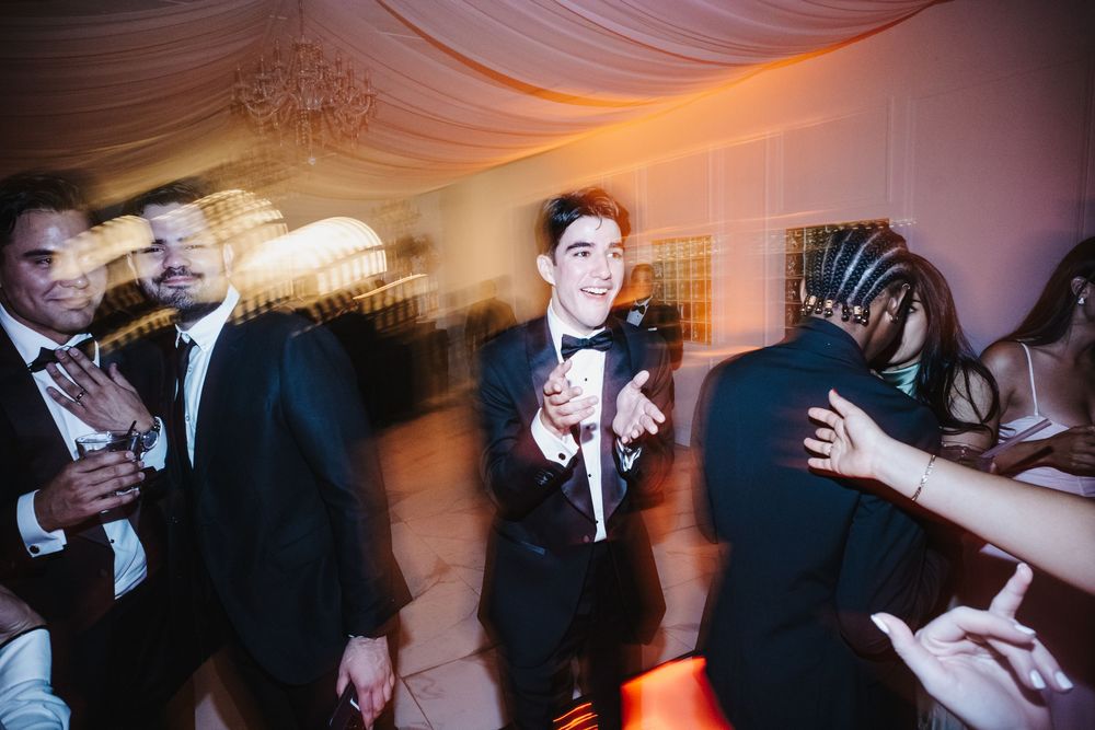 Motion-blurred dance floor scene at a wedding reception with colorful lighting and formal attire.