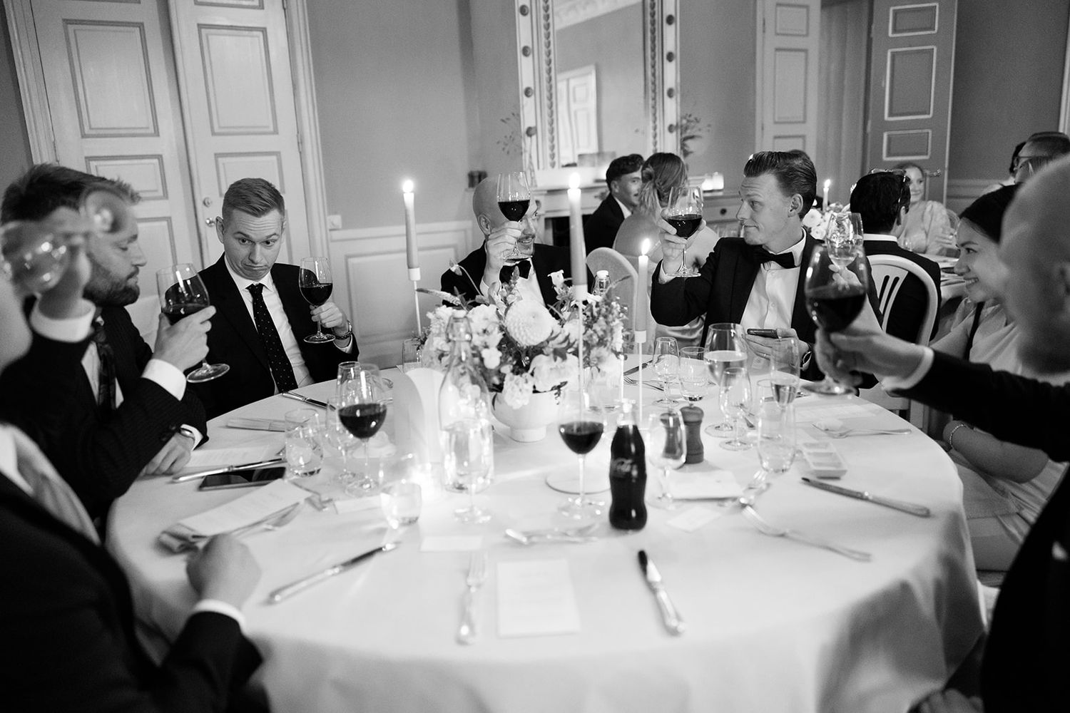 Guests enjoy dinner and conversation at an elegant black and white formal event with candlelit round tables.