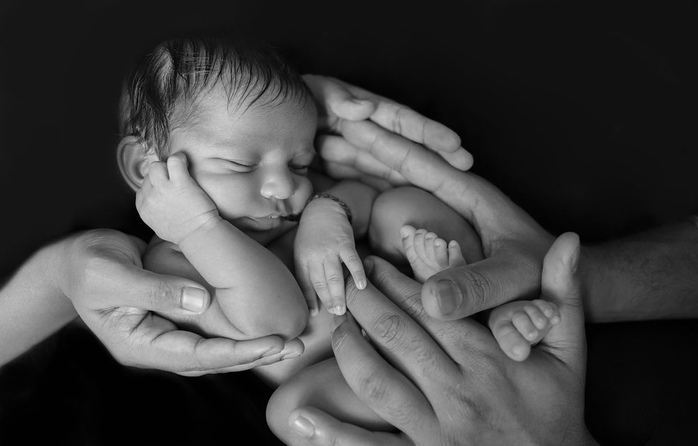 black and white timeless classic of new baby boy in parent's hands. Holding the connection and bond, beautiful baby sleeping and relaxed.