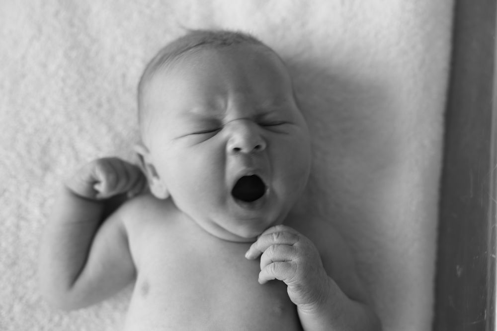 Sleepy baby girl hours after birth taking a deep yawn ready for a sleep. Relaxed documentary style natural and raw.