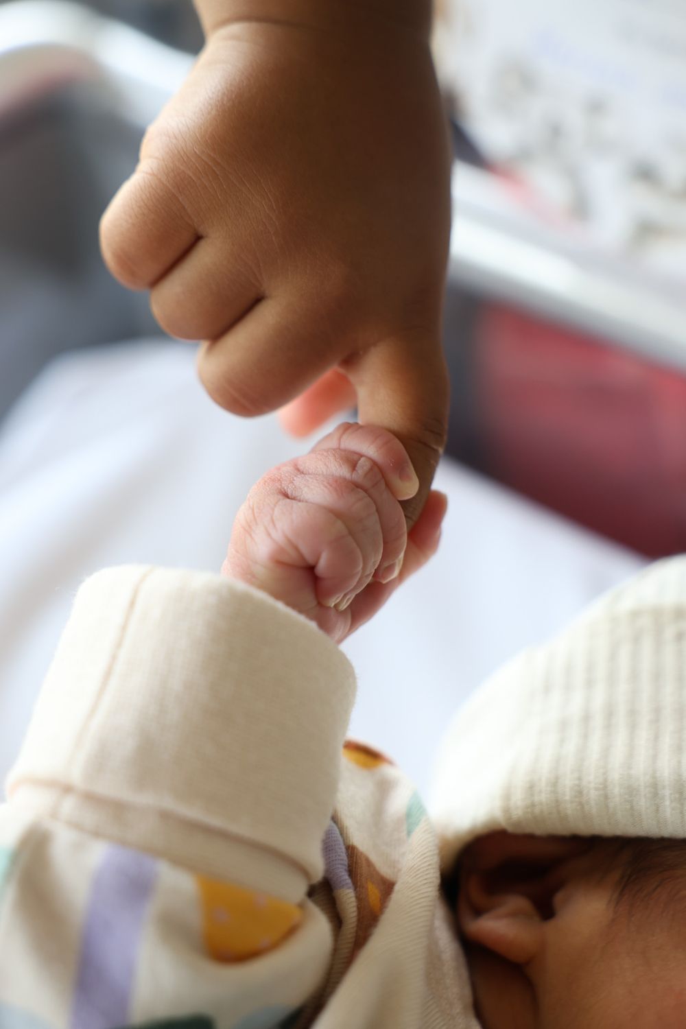 Sibling meeting his newborn sister for the first time at the hospital. Holding her finger at Norwest Private Hospital.