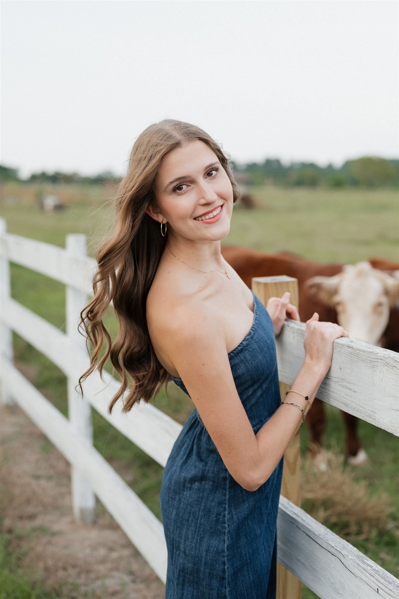 The Woodlands High School senior girl in a denim dress posing for pictures in Magnolia, Texas