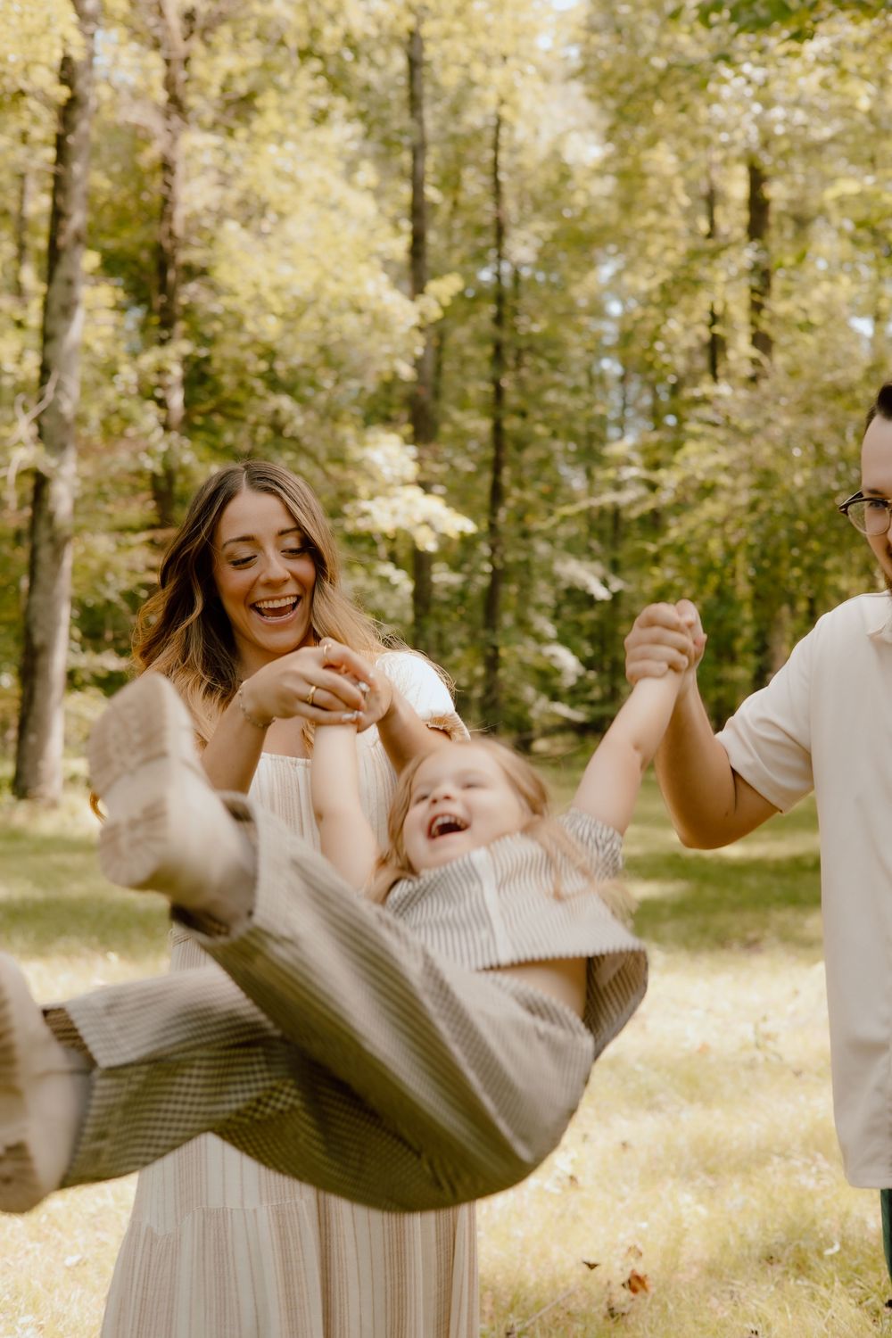 Three candid photos show joyful moments between people in white dresses playing and laughing together in a sunny forest setting.
