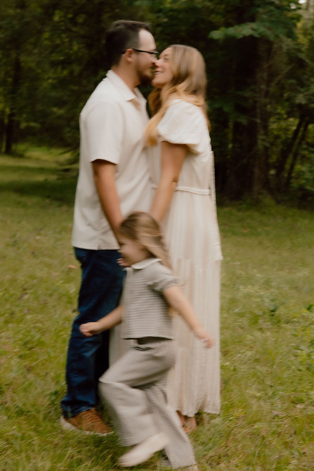 A couple embraces while dancing together in a sunlit wooded area on a warm summer day.
